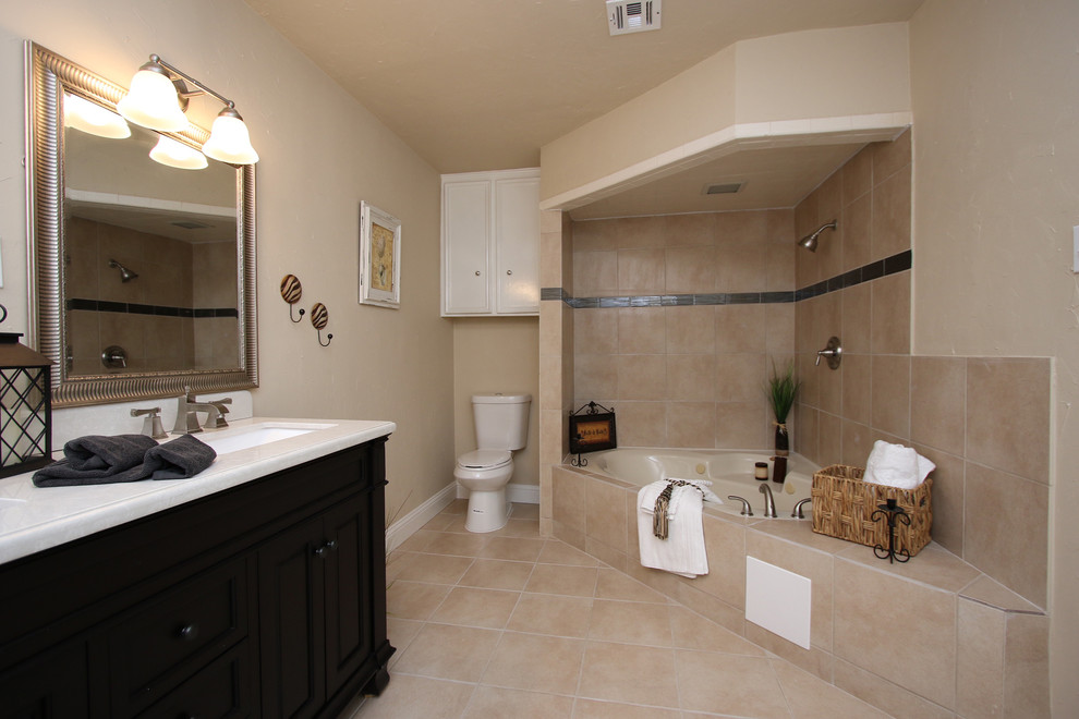 Large traditional ensuite bathroom in Other with recessed-panel cabinets, black cabinets, a corner bath, a shower/bath combination, a two-piece toilet, brown tiles, ceramic tiles, brown walls, cement flooring, a submerged sink, marble worktops, brown floors, an open shower and white worktops.