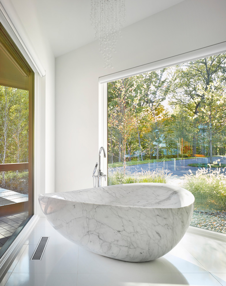 На фото: ванная комната в современном стиле с отдельно стоящей ванной, белыми стенами и белым полом с
