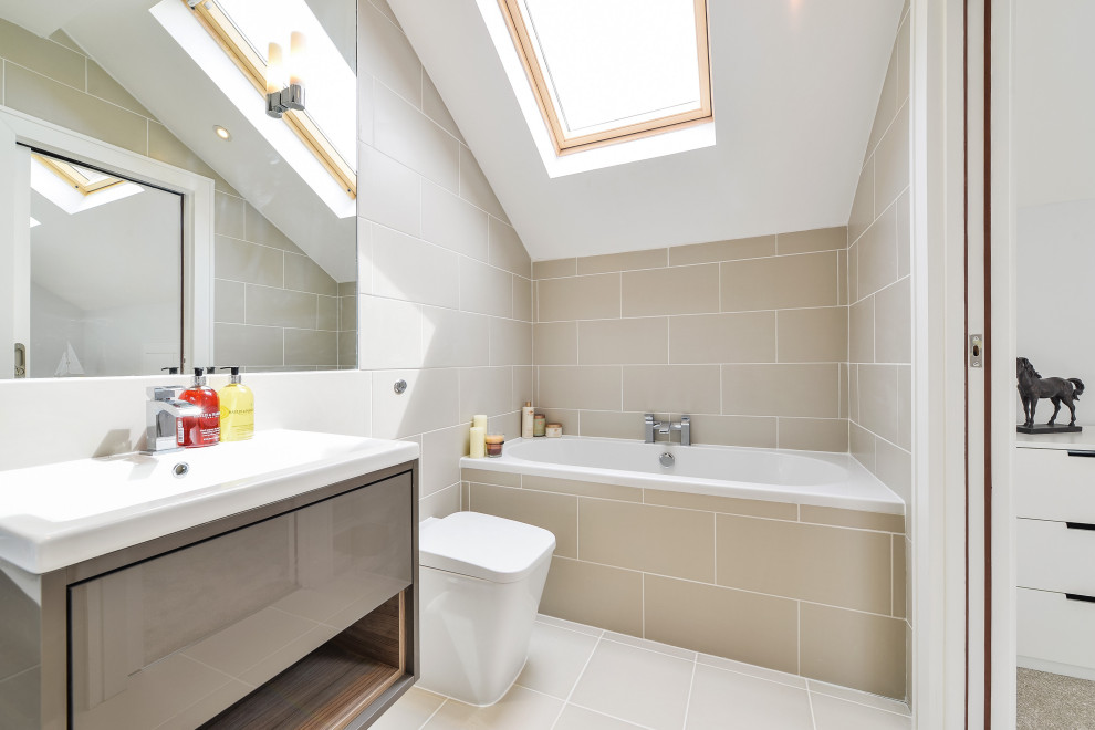 Modernes Badezimmer mit flächenbündigen Schrankfronten, grauen Schränken, Badewanne in Nische, grauen Fliesen, Waschtischkonsole, grauem Boden und gewölbter Decke in London