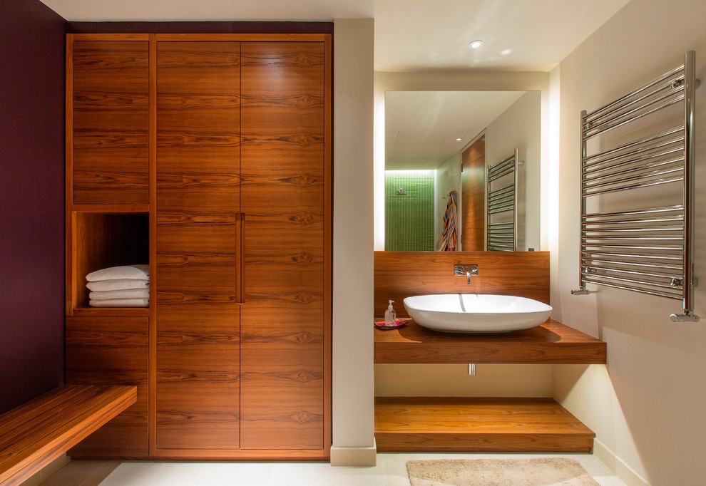 На фото: ванная комната в современном стиле с настольной раковиной, плоскими фасадами, фасадами цвета дерева среднего тона, столешницей из дерева и бежевыми стенами с