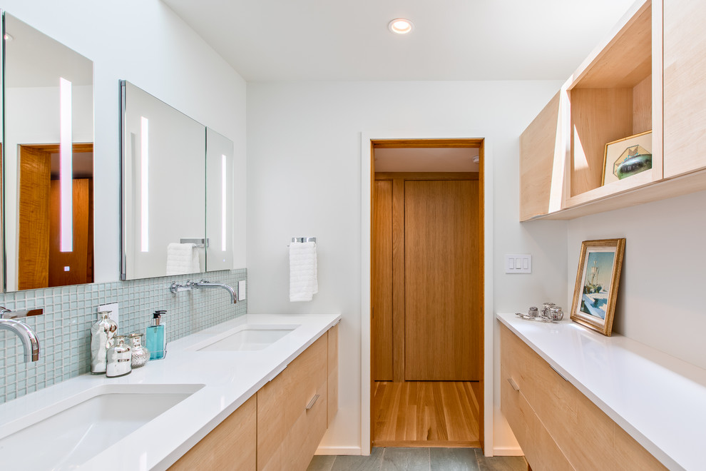 This is an example of a medium sized classic ensuite bathroom in Detroit with flat-panel cabinets, light wood cabinets, a freestanding bath, an alcove shower, glass tiles, white walls, slate flooring, a submerged sink, quartz worktops, grey floors, a hinged door, blue tiles, white worktops and a wall mounted toilet.