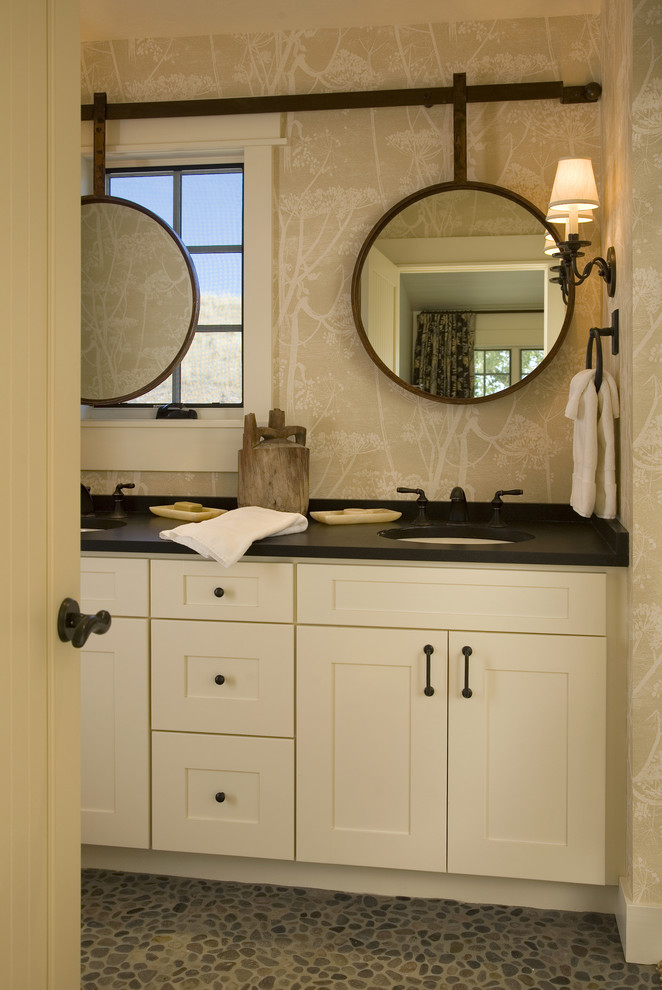 Cette image montre une salle de bain victorienne de taille moyenne avec un lavabo encastré, un placard avec porte à panneau encastré, des portes de placard beiges, un sol en galet, un carrelage gris, une plaque de galets et un mur beige.