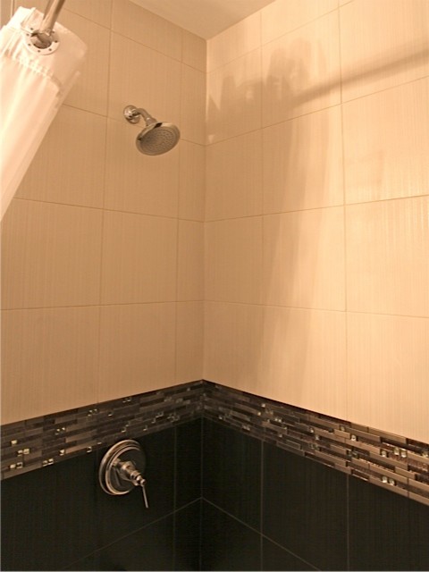 Inredning av ett modernt badrum, med ett undermonterad handfat, ett badkar i en alkov, en dusch/badkar-kombination och en toalettstol med separat cisternkåpa
