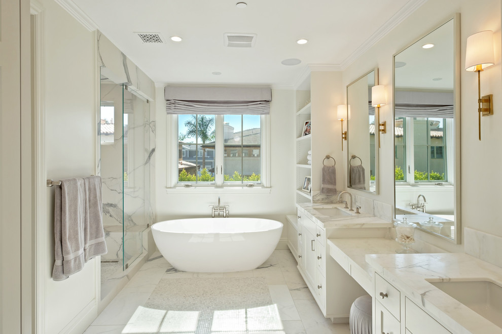 На фото: ванная комната в стиле неоклассика (современная классика) с фасадами в стиле шейкер, белыми фасадами, отдельно стоящей ванной, белой плиткой, белыми стенами, мраморным полом, врезной раковиной, белым полом и белой столешницей