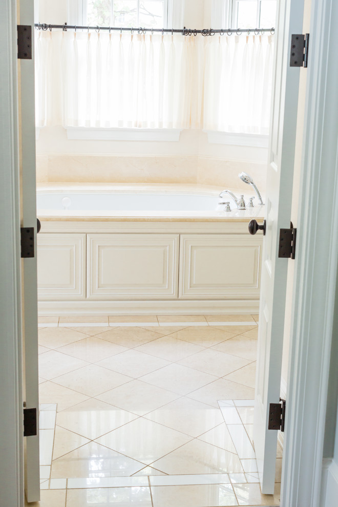 Пример оригинального дизайна: большая главная ванная комната в классическом стиле с фасадами с выступающей филенкой, белыми фасадами, угловой ванной, бежевыми стенами, полом из керамической плитки, врезной раковиной и бежевым полом