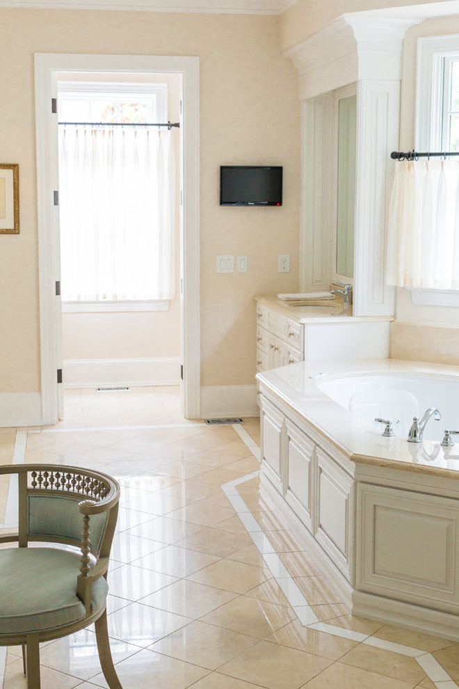 На фото: большая главная ванная комната в классическом стиле с фасадами с выступающей филенкой, белыми фасадами, угловой ванной, бежевыми стенами, полом из керамической плитки, врезной раковиной и бежевым полом с