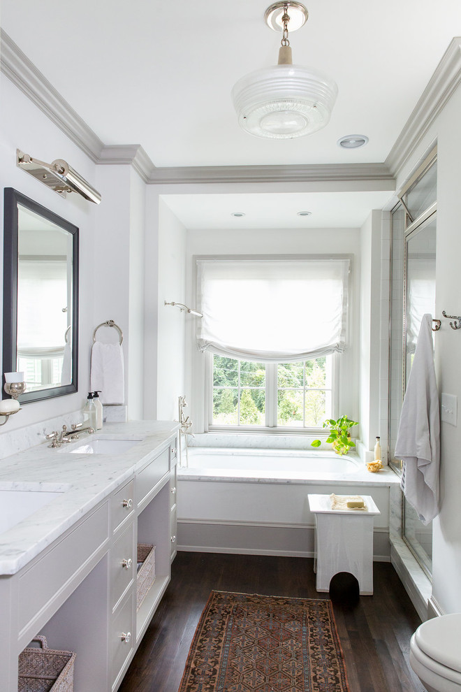 Inspiration for a medium sized classic ensuite bathroom in Raleigh with freestanding cabinets, white cabinets, a submerged bath, a corner shower, white walls, dark hardwood flooring, a submerged sink, marble worktops, brown floors, a hinged door and white worktops.