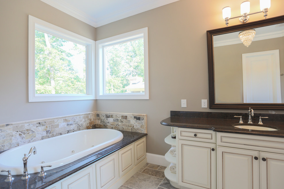 This is an example of a medium sized classic ensuite bathroom in Raleigh with raised-panel cabinets, white cabinets, a built-in bath, beige tiles, cement tiles, beige walls, cement flooring, a submerged sink, granite worktops, beige floors, a corner shower and a hinged door.