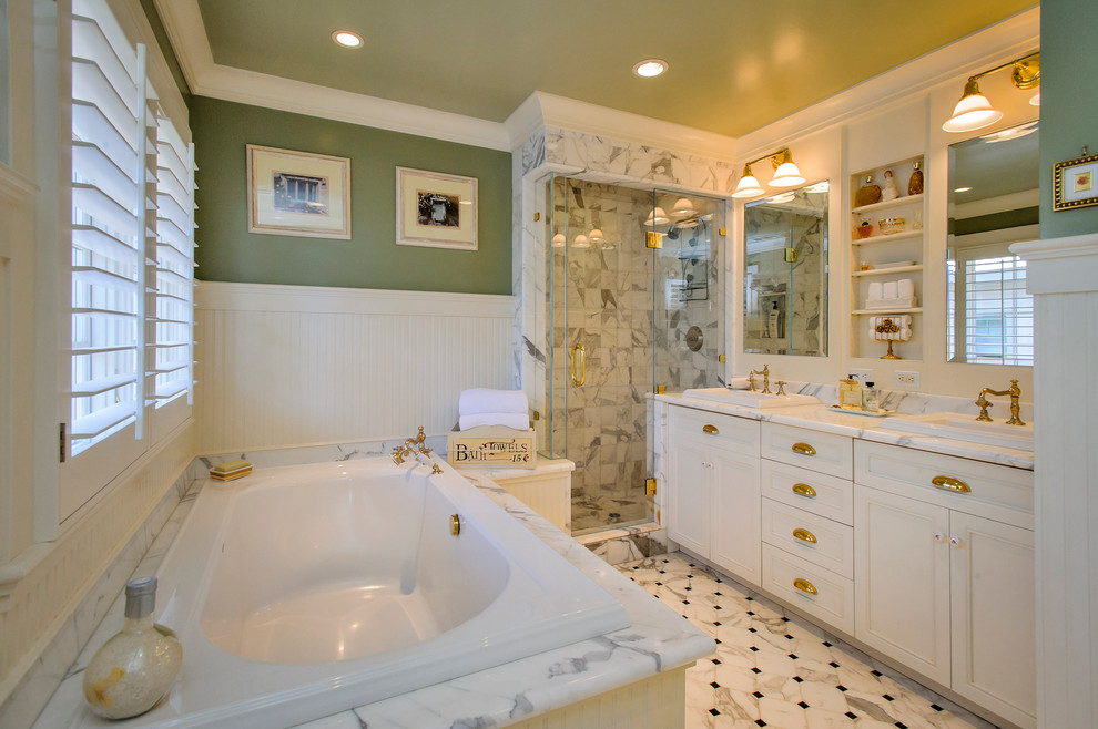 Photo of a medium sized traditional bathroom in San Francisco with a built-in sink, recessed-panel cabinets, white cabinets, a corner shower, white tiles, a built-in bath, stone tiles, green walls, marble flooring, marble worktops, white floors and a hinged door.