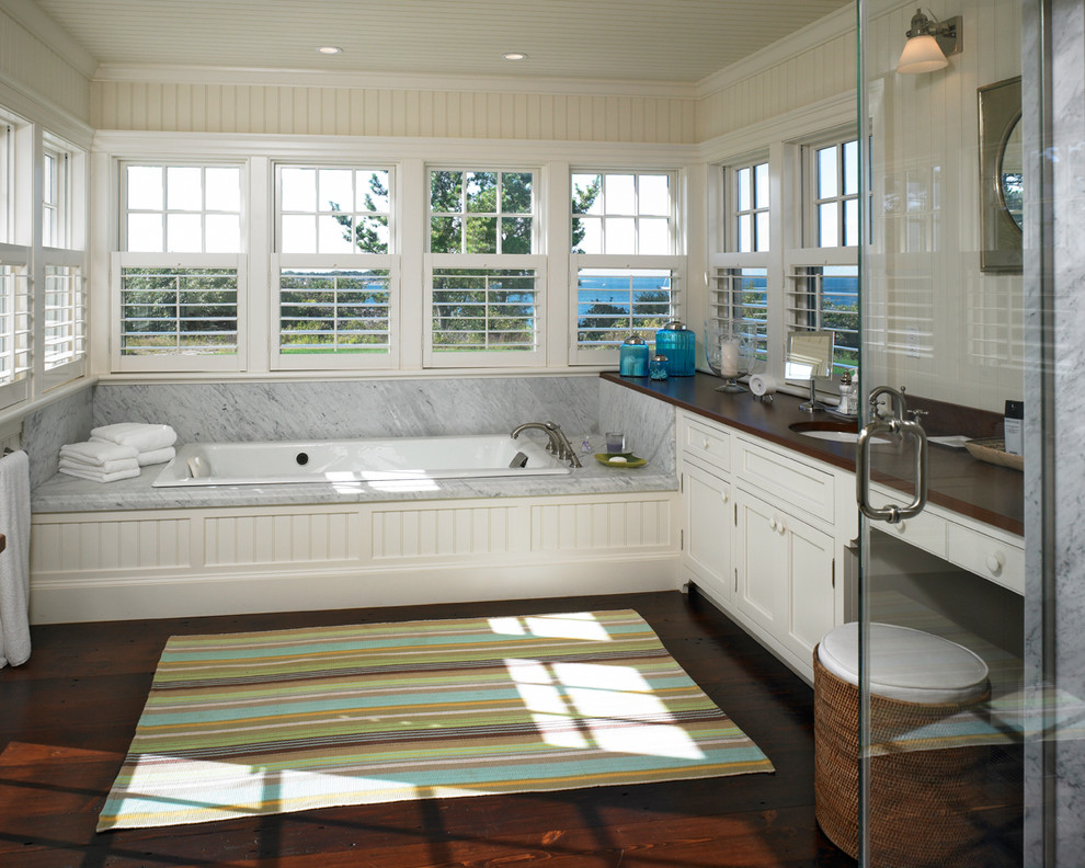 Inspiration for a large coastal ensuite bathroom in Boston with a built-in bath, a submerged sink, beaded cabinets, white cabinets, wooden worktops, a corner shower, white walls, dark hardwood flooring and brown worktops.