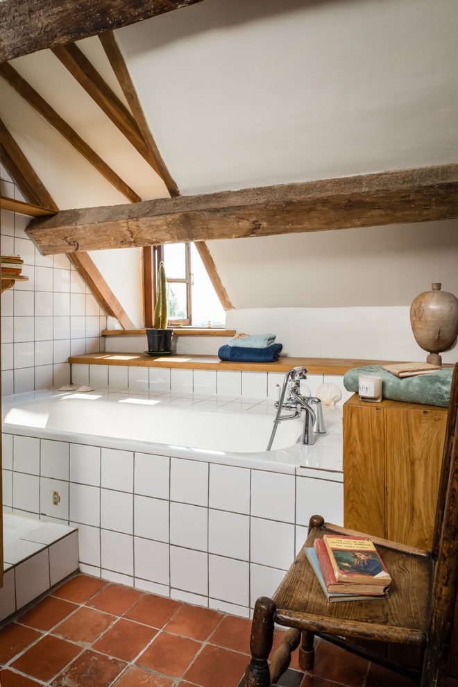 Inredning av ett mellanstort en-suite badrum, med ett platsbyggt badkar, en dusch/badkar-kombination, vit kakel, keramikplattor, vita väggar, klinkergolv i terrakotta, ett väggmonterat handfat och orange golv