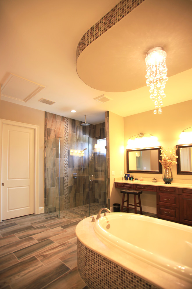 Klassisk inredning av ett stort en-suite badrum, med luckor med upphöjd panel, skåp i mellenmörkt trä, ett fristående badkar, en hörndusch, en toalettstol med hel cisternkåpa, beige väggar, laminatgolv, ett undermonterad handfat, marmorbänkskiva, flerfärgat golv och dusch med gångjärnsdörr