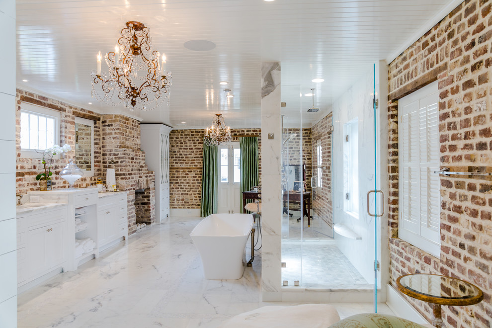 Klassisk inredning av ett mycket stort en-suite badrum, med luckor med profilerade fronter, vita skåp, ett fristående badkar, en dubbeldusch, en toalettstol med separat cisternkåpa, marmorgolv, ett undermonterad handfat, marmorbänkskiva, vitt golv och dusch med gångjärnsdörr
