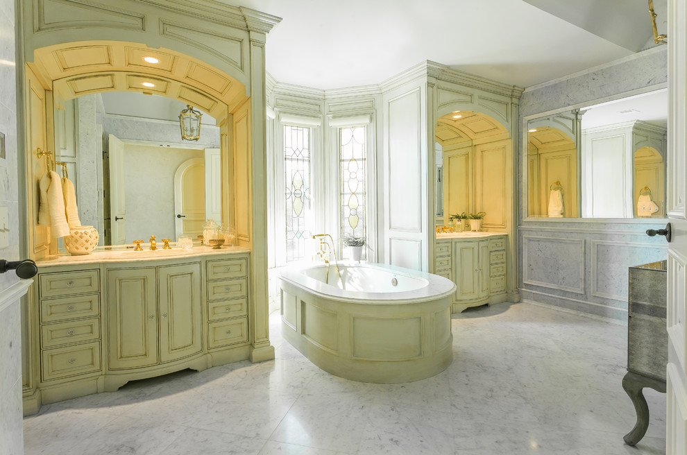 Large master freestanding bathtub photo in Charleston with white cabinets, white walls and marble countertops