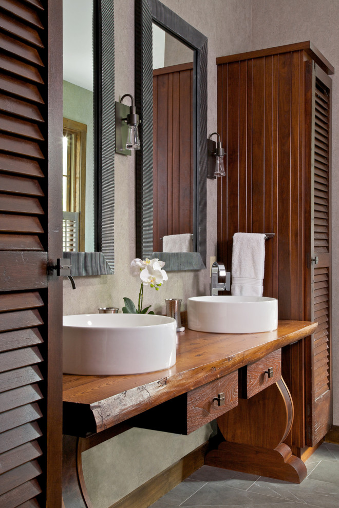 Example of a mountain style gray floor bathroom design in Other with furniture-like cabinets, medium tone wood cabinets, a vessel sink, wood countertops and brown countertops