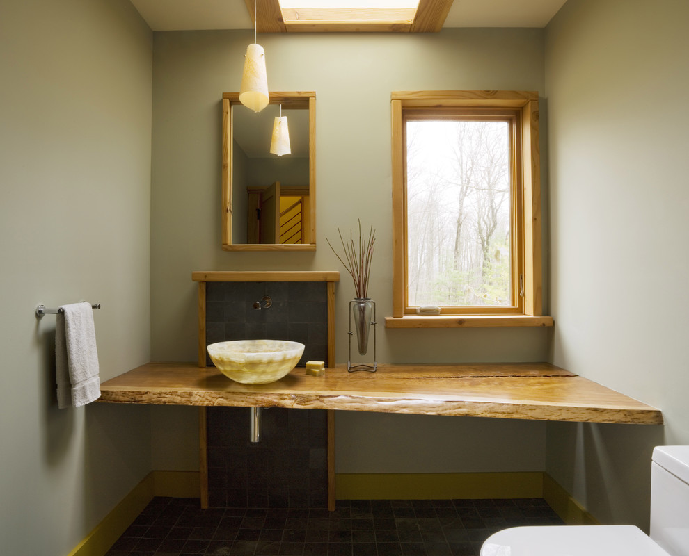 Modelo de cuarto de baño moderno con lavabo sobreencimera, encimera de madera y encimeras marrones
