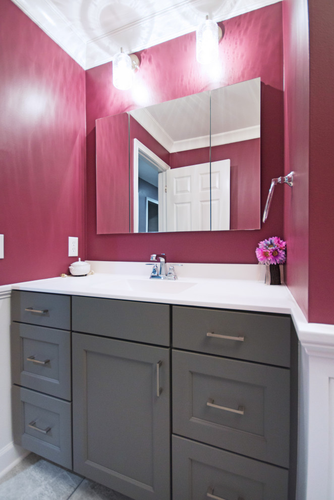 Esempio di una stanza da bagno moderna di medie dimensioni con ante con riquadro incassato, ante grigie, WC a due pezzi, pareti rosa, pavimento in gres porcellanato, lavabo integrato, top in superficie solida, pavimento grigio e top bianco