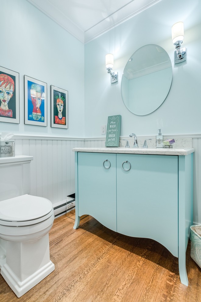 Idée de décoration pour une salle de bain marine de taille moyenne avec un placard à porte plane, des portes de placard bleues, WC à poser, un mur vert, parquet clair, un lavabo encastré et un plan de toilette en quartz modifié.