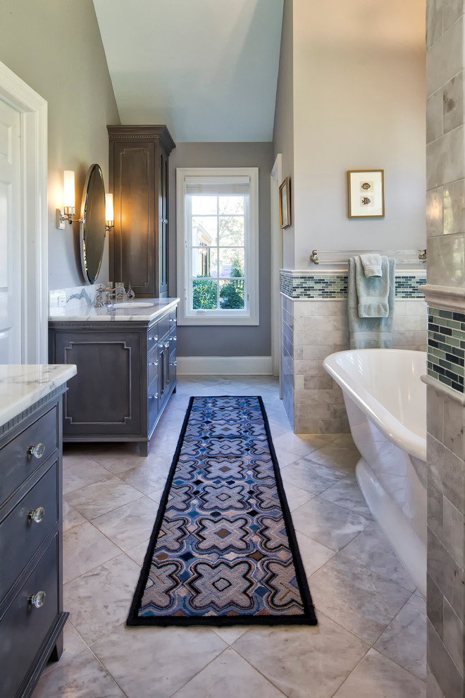 Пример оригинального дизайна: главная ванная комната в классическом стиле с серыми фасадами, отдельно стоящей ванной, серой плиткой, фасадами с декоративным кантом, душем в нише, унитазом-моноблоком, мраморной плиткой, серыми стенами, мраморным полом, врезной раковиной, мраморной столешницей, серым полом, душем с распашными дверями и белой столешницей