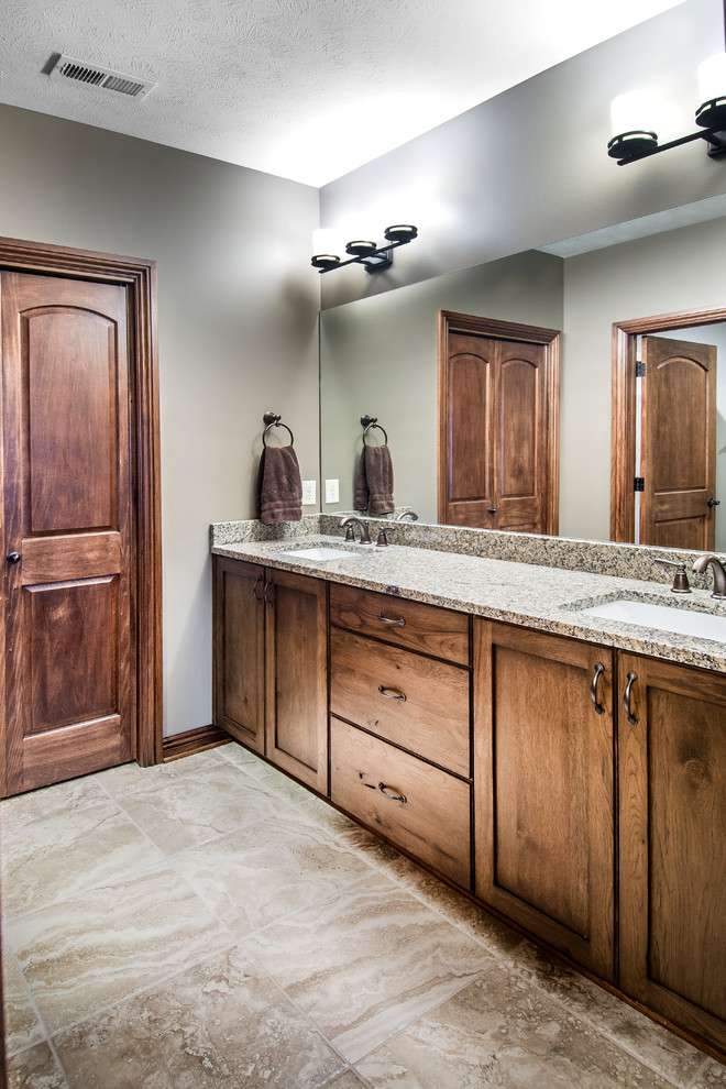 Photo of a medium sized rustic shower room bathroom in Omaha with a submerged sink, shaker cabinets, dark wood cabinets, granite worktops, an alcove bath, a two-piece toilet, beige tiles, ceramic tiles, beige walls, ceramic flooring, brown floors and grey worktops.
