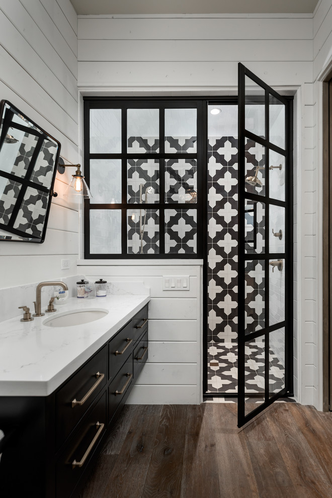 Inspiration for a medium sized mediterranean bathroom in Phoenix with black cabinets, an alcove shower, black and white tiles, ceramic tiles, white walls, dark hardwood flooring, a built-in sink, marble worktops, brown floors, a hinged door, white worktops, a single sink, a floating vanity unit and tongue and groove walls.