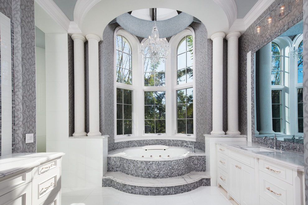 Design ideas for a classic ensuite bathroom in Miami with recessed-panel cabinets, white cabinets, a hot tub, grey tiles, mosaic tiles, grey walls, a submerged sink and white floors.