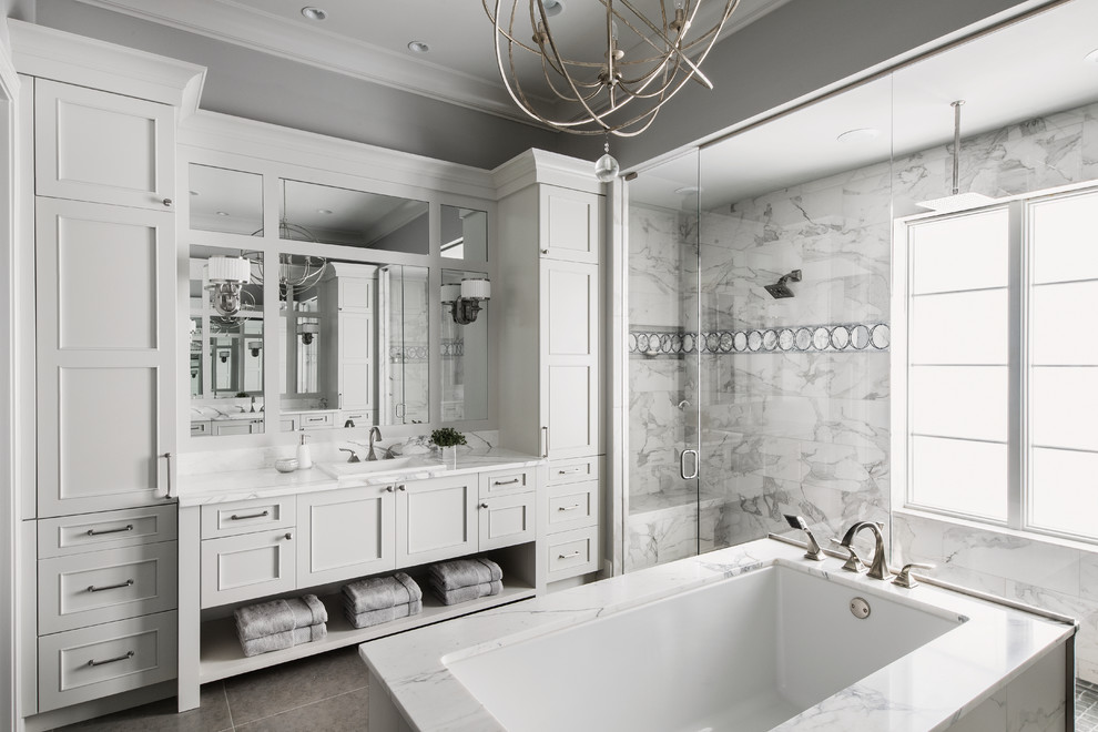 Свежая идея для дизайна: главная ванная комната в классическом стиле с фасадами с утопленной филенкой, белыми фасадами, полновстраиваемой ванной, душевой комнатой, серой плиткой, серыми стенами, накладной раковиной, серым полом и душем с распашными дверями - отличное фото интерьера