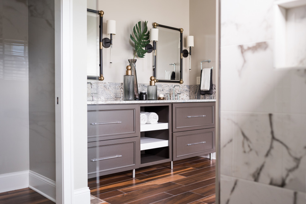 Example of a mid-sized trendy master beige tile and ceramic tile medium tone wood floor bathroom design in Indianapolis with shaker cabinets, gray cabinets, gray walls, an undermount sink, granite countertops, a hinged shower door and gray countertops