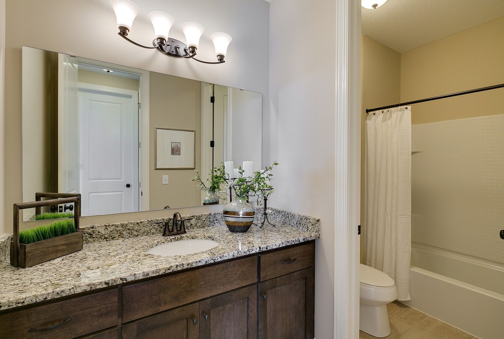 Imagen de cuarto de baño costero con encimera de granito, paredes blancas, suelo de baldosas de cerámica y puertas de armario de madera en tonos medios