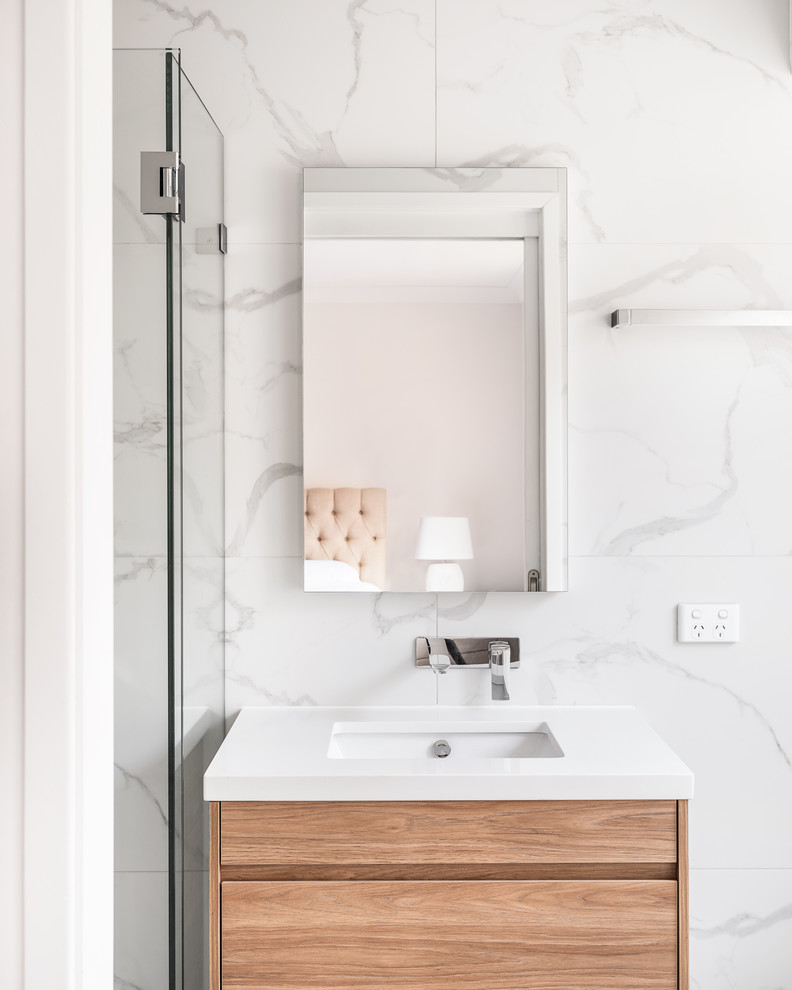 Пример оригинального дизайна: главная ванная комната среднего размера в современном стиле с фасадами с утопленной филенкой, коричневыми фасадами, накладной ванной, угловым душем, унитазом-моноблоком, белой плиткой, мраморной плиткой, белыми стенами, полом из цементной плитки, врезной раковиной, столешницей из искусственного камня, серым полом, душем с распашными дверями и белой столешницей