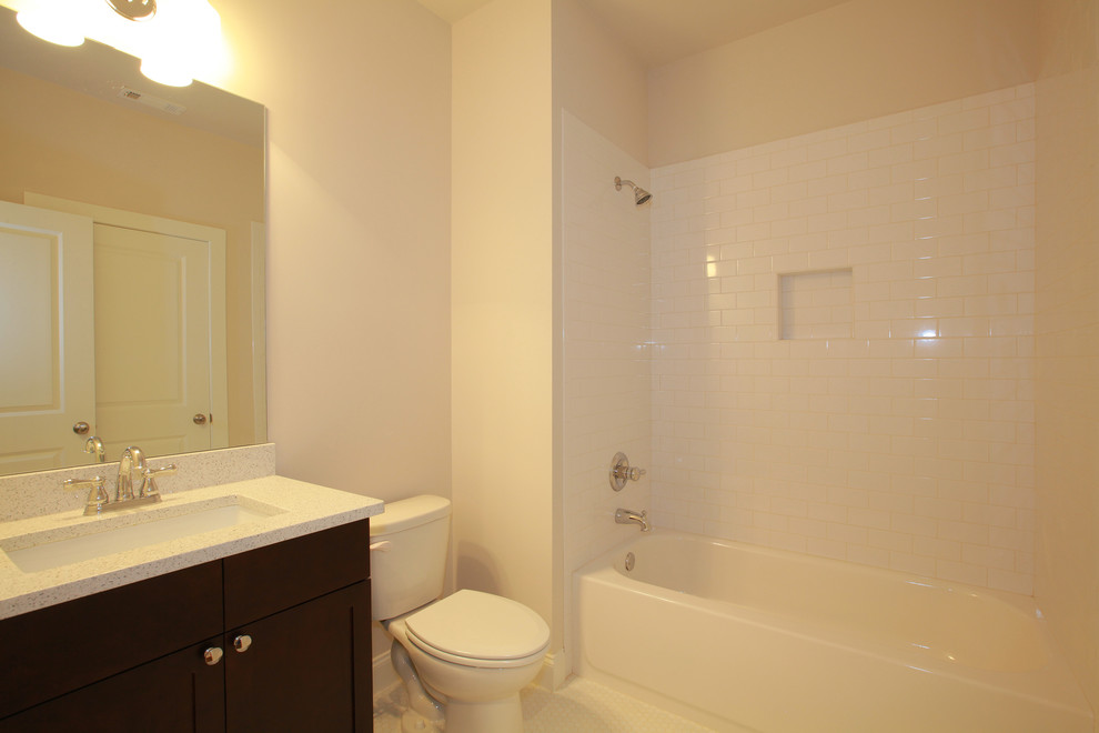 Cette image montre une salle de bain rustique en bois foncé avec un placard avec porte à panneau encastré, un plan de toilette en granite, un combiné douche/baignoire, un carrelage blanc, un carrelage métro, un mur beige et un sol en carrelage de céramique.