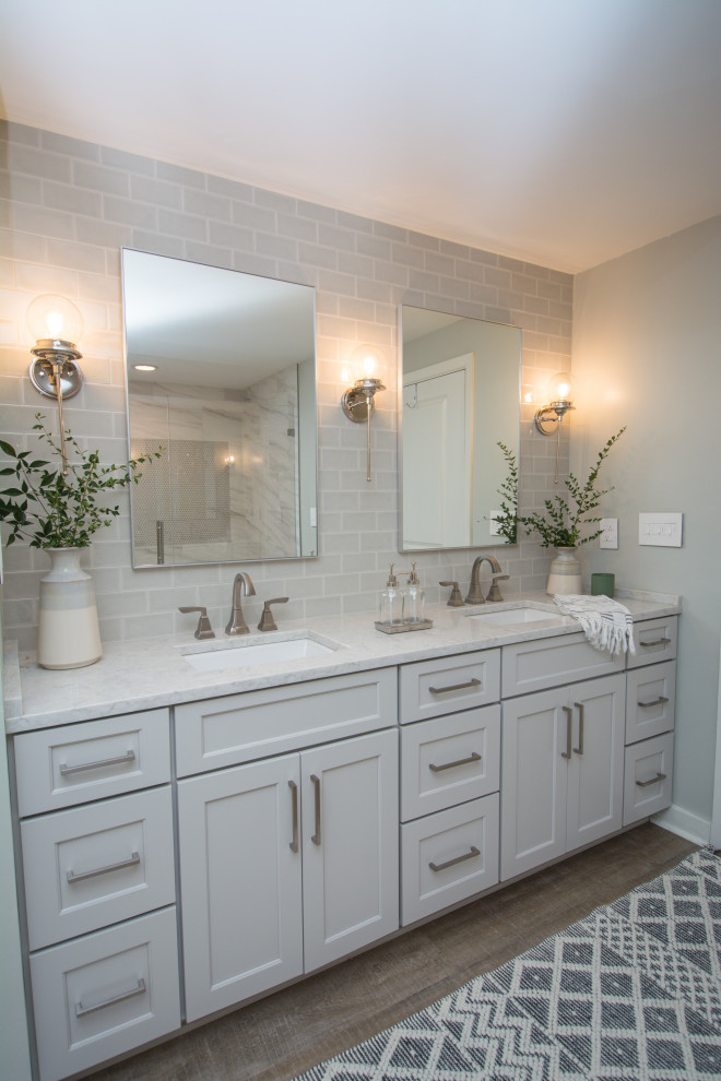 Foto på ett litet vintage vit en-suite badrum, med skåp i shakerstil, vita skåp, en dusch i en alkov, grå kakel, glaskakel, grå väggar, laminatgolv, ett undermonterad handfat, bänkskiva i kvartsit, brunt golv och dusch med gångjärnsdörr