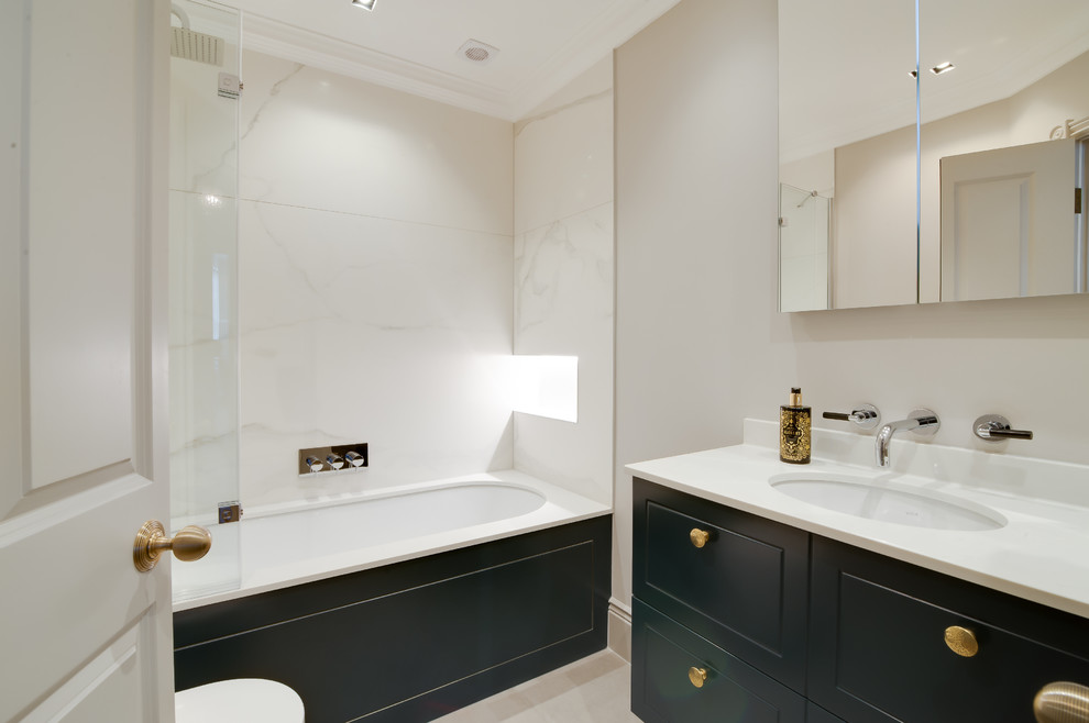 На фото: ванная комната среднего размера в стиле неоклассика (современная классика) с душем над ванной, белой плиткой, плиткой из листового камня, мраморной столешницей, черными фасадами, полновстраиваемой ванной и врезной раковиной