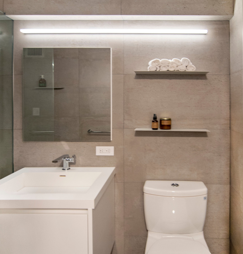 Foto på ett litet funkis vit en-suite badrum, med släta luckor, vita skåp, ett platsbyggt badkar, en dusch/badkar-kombination, en toalettstol med hel cisternkåpa, grå kakel, porslinskakel, grå väggar, klinkergolv i porslin, ett integrerad handfat, bänkskiva i akrylsten, grått golv och med dusch som är öppen