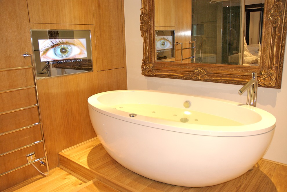 This is an example of a modern bathroom in London with a vessel sink, a freestanding bath and a wall mounted toilet.