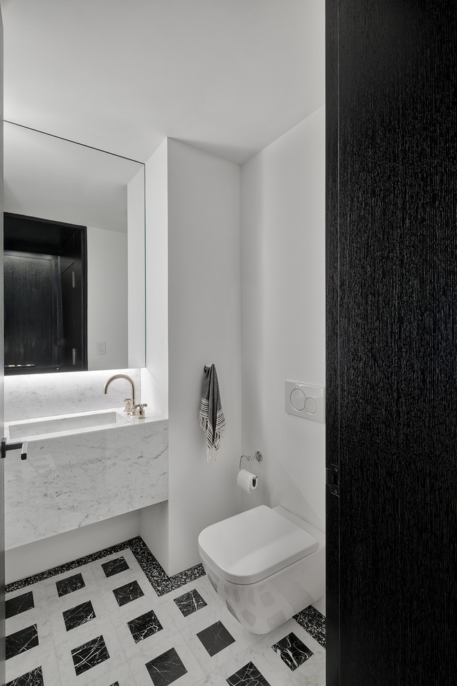 ニューヨークにある小さなコンテンポラリースタイルのおしゃれな浴室 (壁掛け式トイレ、白い壁、大理石の床、横長型シンク、テラゾーの洗面台、マルチカラーの床、白い洗面カウンター) の写真