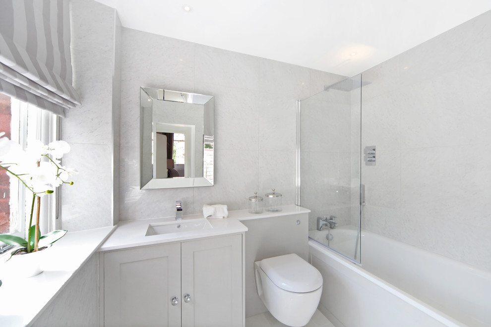 Photo of a small classic ensuite bathroom in London with grey cabinets, an alcove bath, a wall mounted toilet, marble tiles, grey walls, white worktops, shaker cabinets, a shower/bath combination, grey tiles, a submerged sink and an open shower.