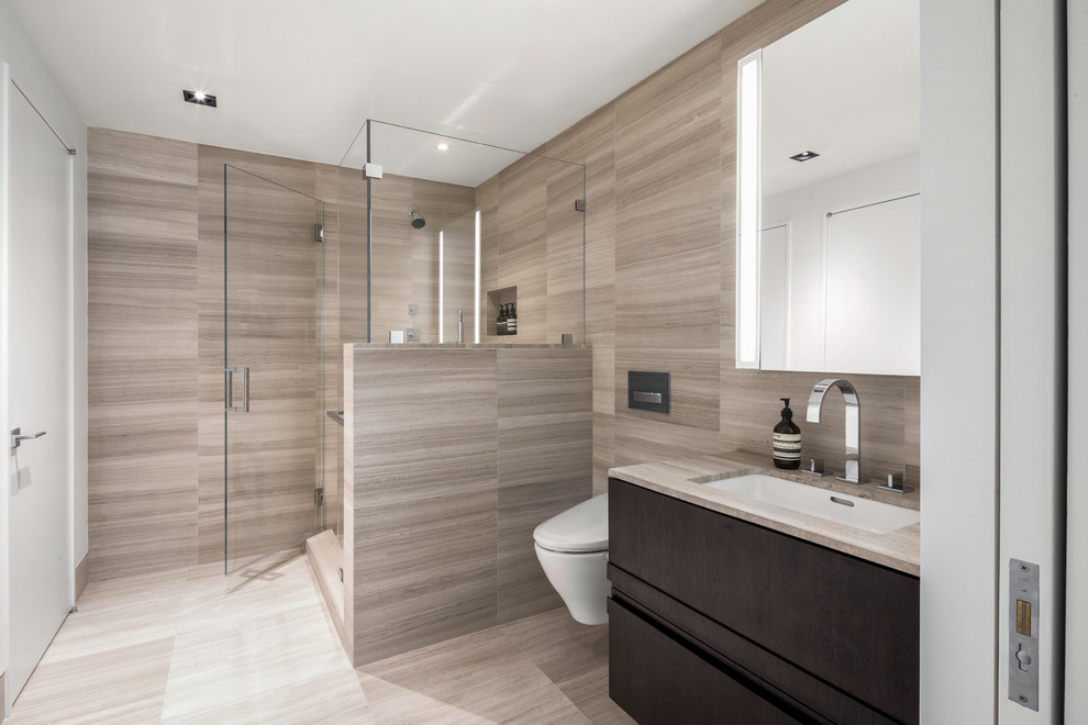 This is an example of a medium sized contemporary shower room bathroom in New York with a corner shower, a wall mounted toilet, beige tiles, marble tiles, marble flooring, a submerged sink, marble worktops, beige floors, a hinged door and beige worktops.