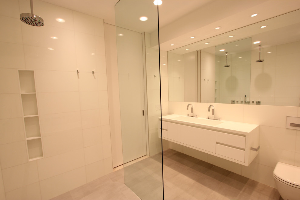Ispirazione per una stanza da bagno padronale design di medie dimensioni con lavabo integrato, ante lisce, ante bianche, vasca ad alcova, vasca/doccia, WC monopezzo e pareti bianche