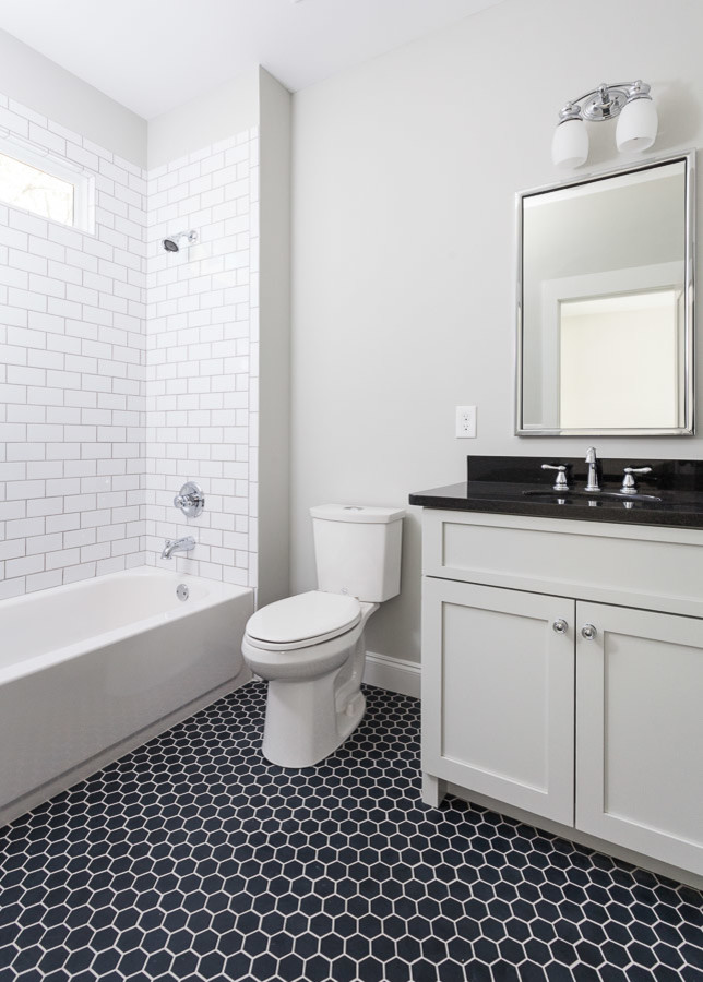 Design ideas for a medium sized traditional shower room bathroom in Atlanta with shaker cabinets, grey cabinets, an alcove bath, a shower/bath combination, a two-piece toilet, white tiles, metro tiles, grey walls, porcelain flooring, a submerged sink, solid surface worktops, black floors and black worktops.