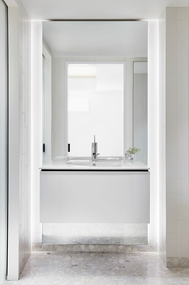 ニューヨークにある中くらいなコンテンポラリースタイルのおしゃれなバスルーム (浴槽なし) (フラットパネル扉のキャビネット、白いキャビネット、アルコーブ型シャワー、一体型シンク、人工大理石カウンター、白い床、開き戸のシャワー、白い洗面カウンター、白い壁) の写真