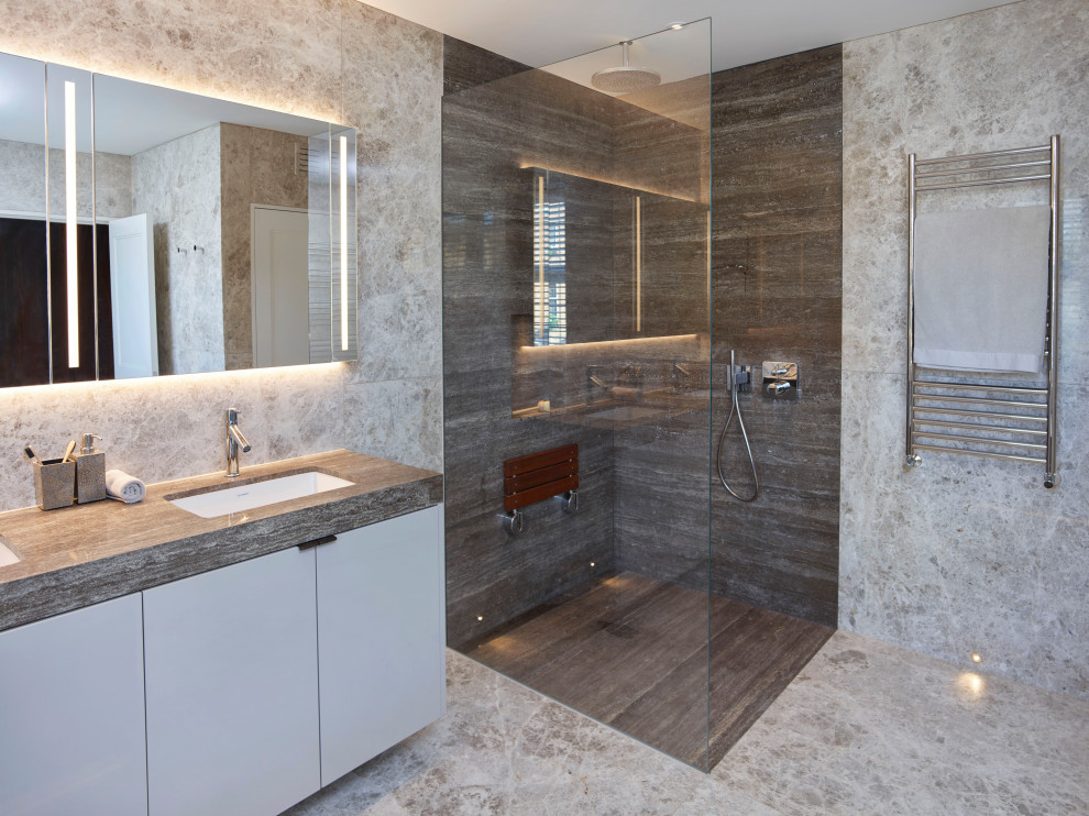 Modern inredning av ett stort grå grått en-suite badrum, med släta luckor, grå skåp, en hörndusch, grå kakel, porslinskakel, klinkergolv i porslin, ett undermonterad handfat, grått golv och med dusch som är öppen