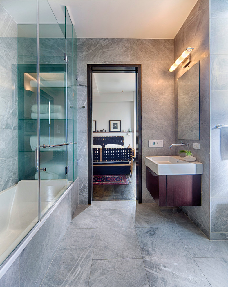Inspiration for an urban ensuite bathroom in New York with freestanding cabinets, dark wood cabinets, a shower/bath combination, grey tiles, grey walls, a corner bath, a one-piece toilet, ceramic tiles, ceramic flooring, a trough sink, grey floors and an open shower.