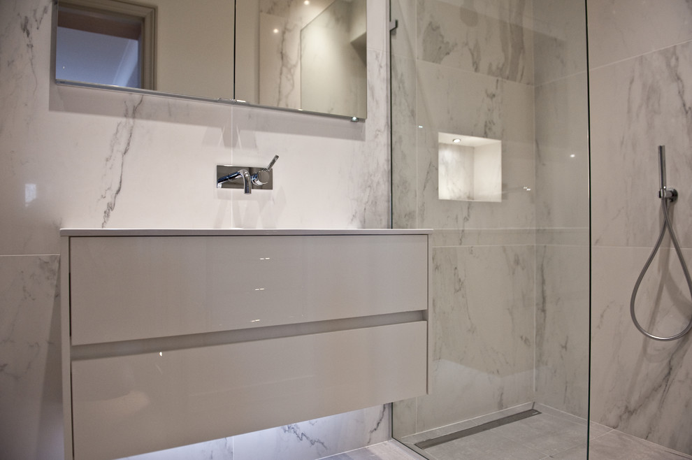 Design ideas for a small contemporary ensuite bathroom in London with white cabinets, a walk-in shower, a one-piece toilet, grey tiles, stone tiles, grey walls and a wall-mounted sink.