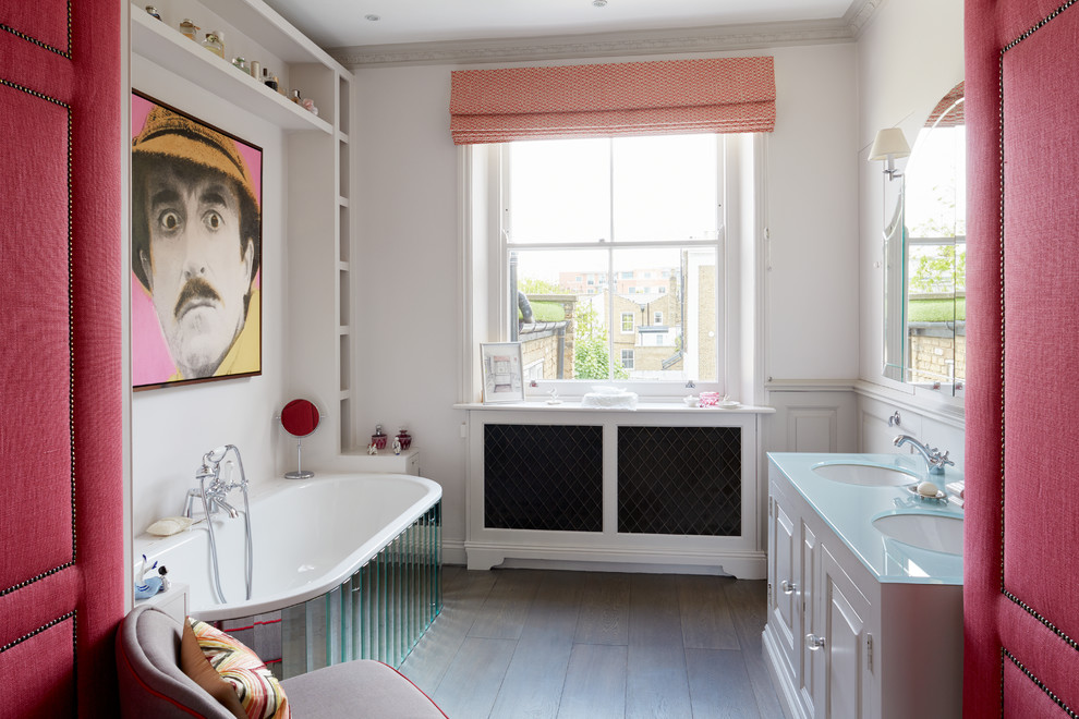 ロンドンにある中くらいなエクレクティックスタイルのおしゃれなマスターバスルーム (レイズドパネル扉のキャビネット、白いキャビネット、ドロップイン型浴槽、白い壁、無垢フローリング、アンダーカウンター洗面器、シャワー付き浴槽	、ガラスの洗面台) の写真