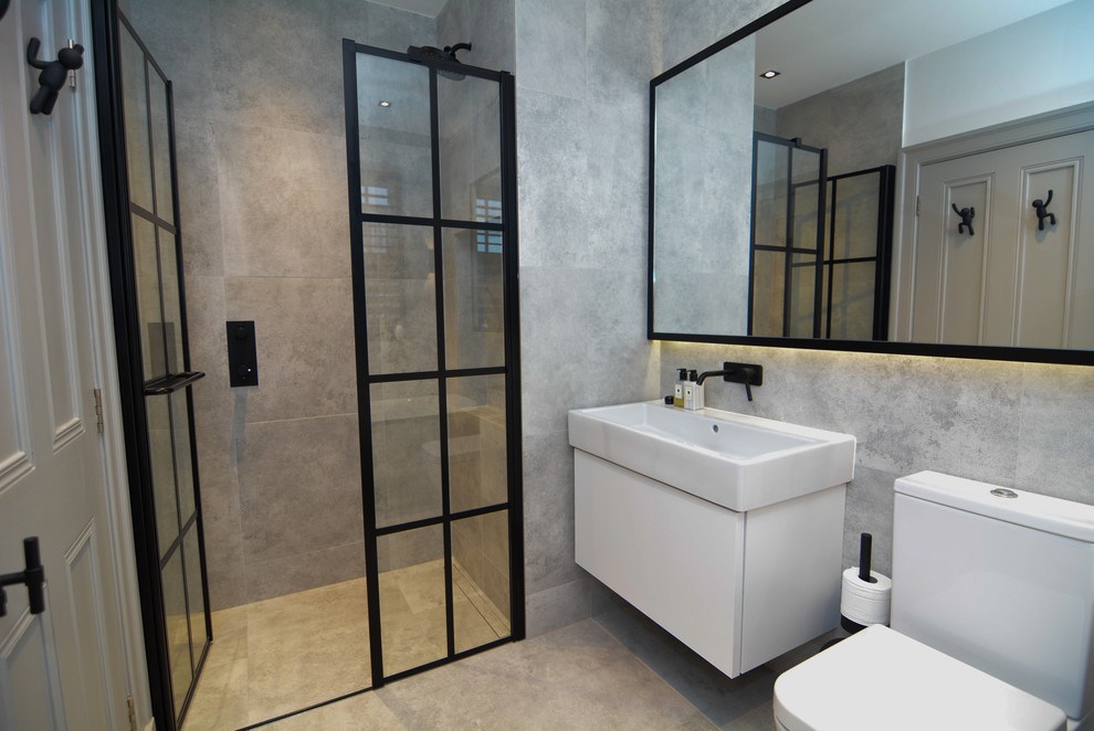 This is an example of a medium sized contemporary ensuite bathroom in London with a freestanding bath, a walk-in shower, grey tiles and a hinged door.