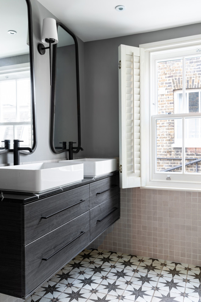 Photo of a medium sized traditional ensuite bathroom in Sussex with flat-panel cabinets, grey cabinets, a walk-in shower, a wall mounted toilet, grey tiles, porcelain tiles, grey walls, ceramic flooring, a console sink, marble worktops, grey floors, black worktops, double sinks and a floating vanity unit.