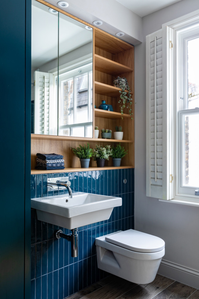 Inspiration pour une salle de bain traditionnelle de taille moyenne pour enfant avec un placard à porte plane, des portes de placard bleues, une baignoire posée, une douche ouverte, WC suspendus, un carrelage bleu, des carreaux de céramique, un mur gris, un sol en carrelage de porcelaine, un lavabo suspendu, un plan de toilette en bois, un sol gris, une cabine de douche à porte battante, un plan de toilette bleu, meuble simple vasque et meuble-lavabo encastré.