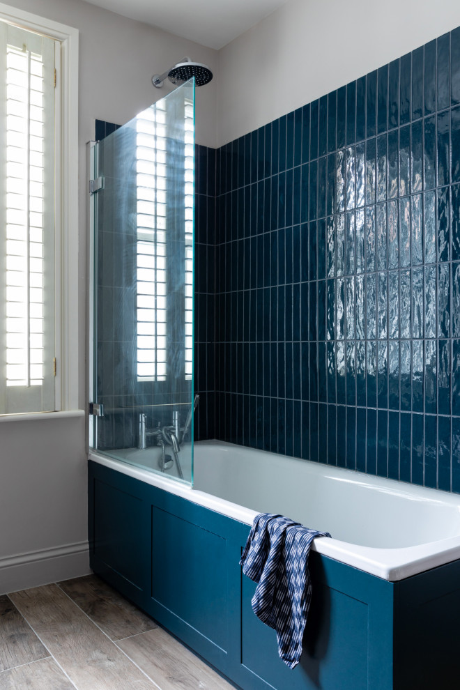 Стильный дизайн: детская ванная комната среднего размера в стиле неоклассика (современная классика) с плоскими фасадами, синими фасадами, накладной ванной, открытым душем, инсталляцией, синей плиткой, керамической плиткой, серыми стенами, полом из керамогранита, подвесной раковиной, столешницей из дерева, серым полом, душем с распашными дверями, синей столешницей, тумбой под одну раковину и встроенной тумбой - последний тренд