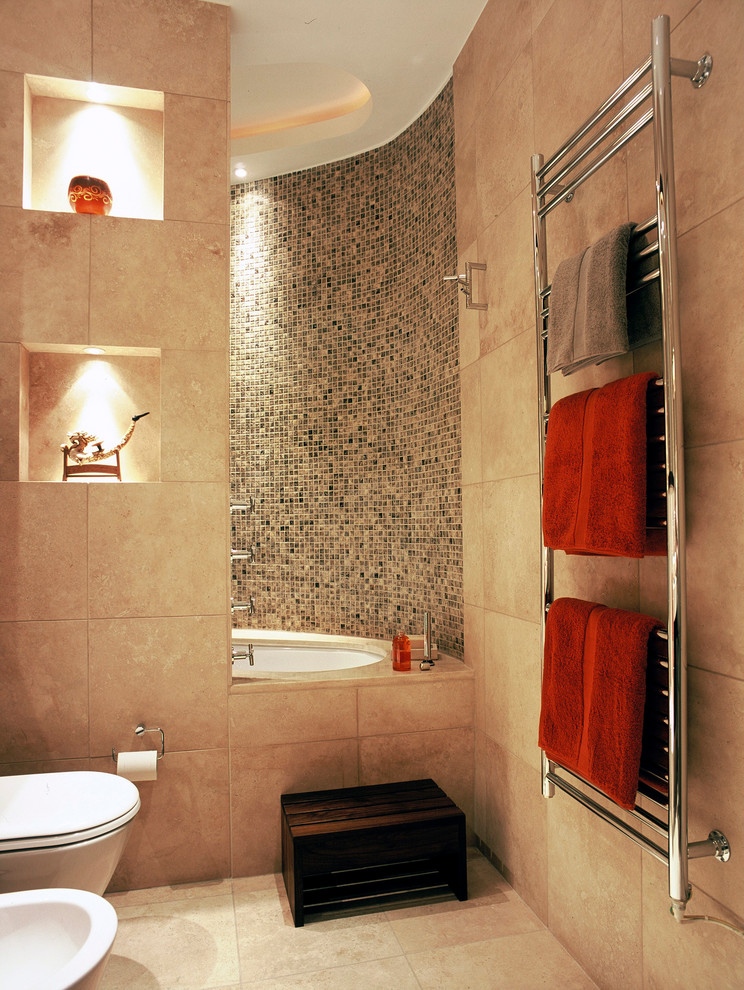 Inspiration for a small contemporary family bathroom in London with flat-panel cabinets, dark wood cabinets, a built-in bath, a shower/bath combination, a wall mounted toilet, beige tiles, limestone tiles, beige walls, limestone flooring, a vessel sink, limestone worktops, beige floors, an open shower and beige worktops.